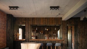 A bar area with a rustic wooden bar counter, stools, and pendant lighting.