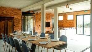 A dining area with a long wooden table set for six, surrounded by chairs.
