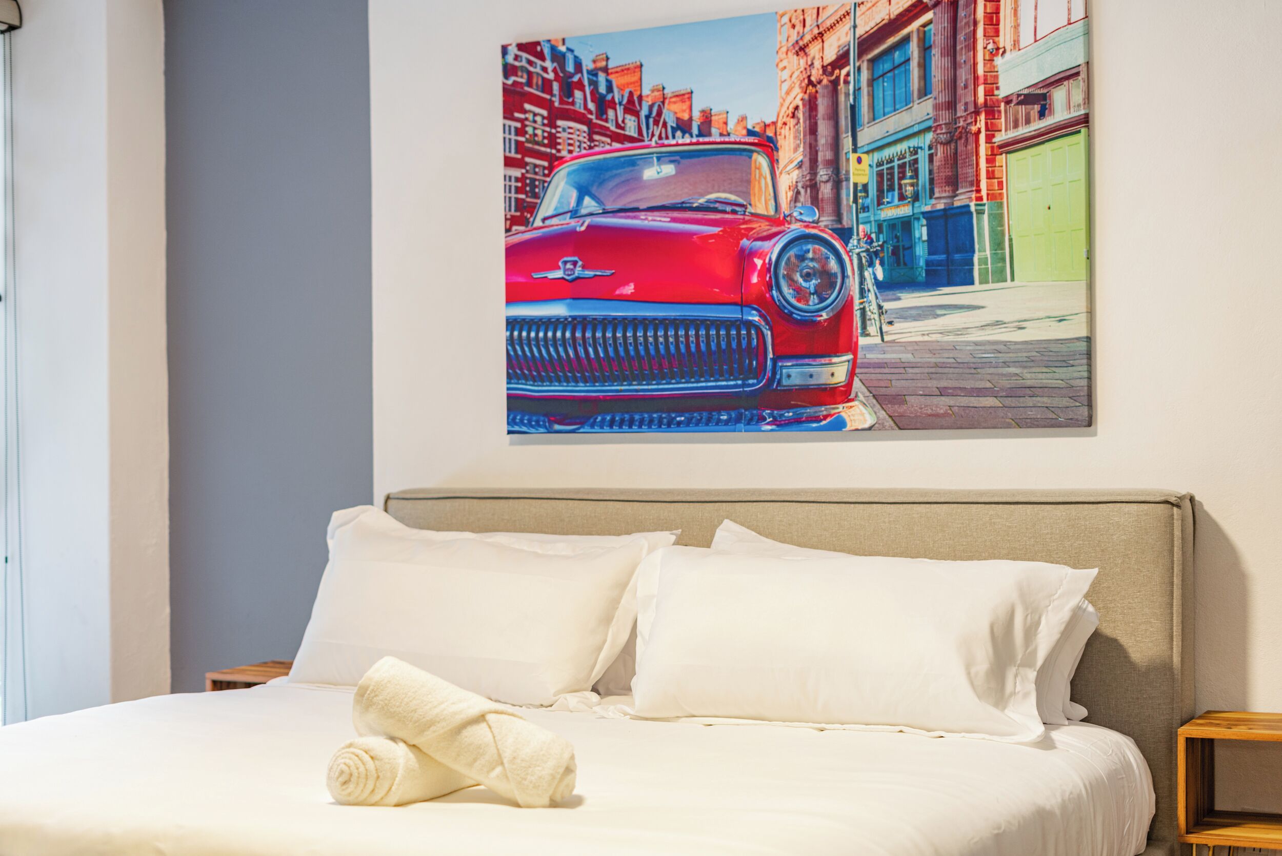 Een hotelkamer met een bed, witte kussens en een opgerolde handdoek.