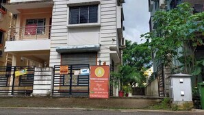 Um edifício com uma placa indicando 'Shree Residency Guest House' e uma entrada com portão.