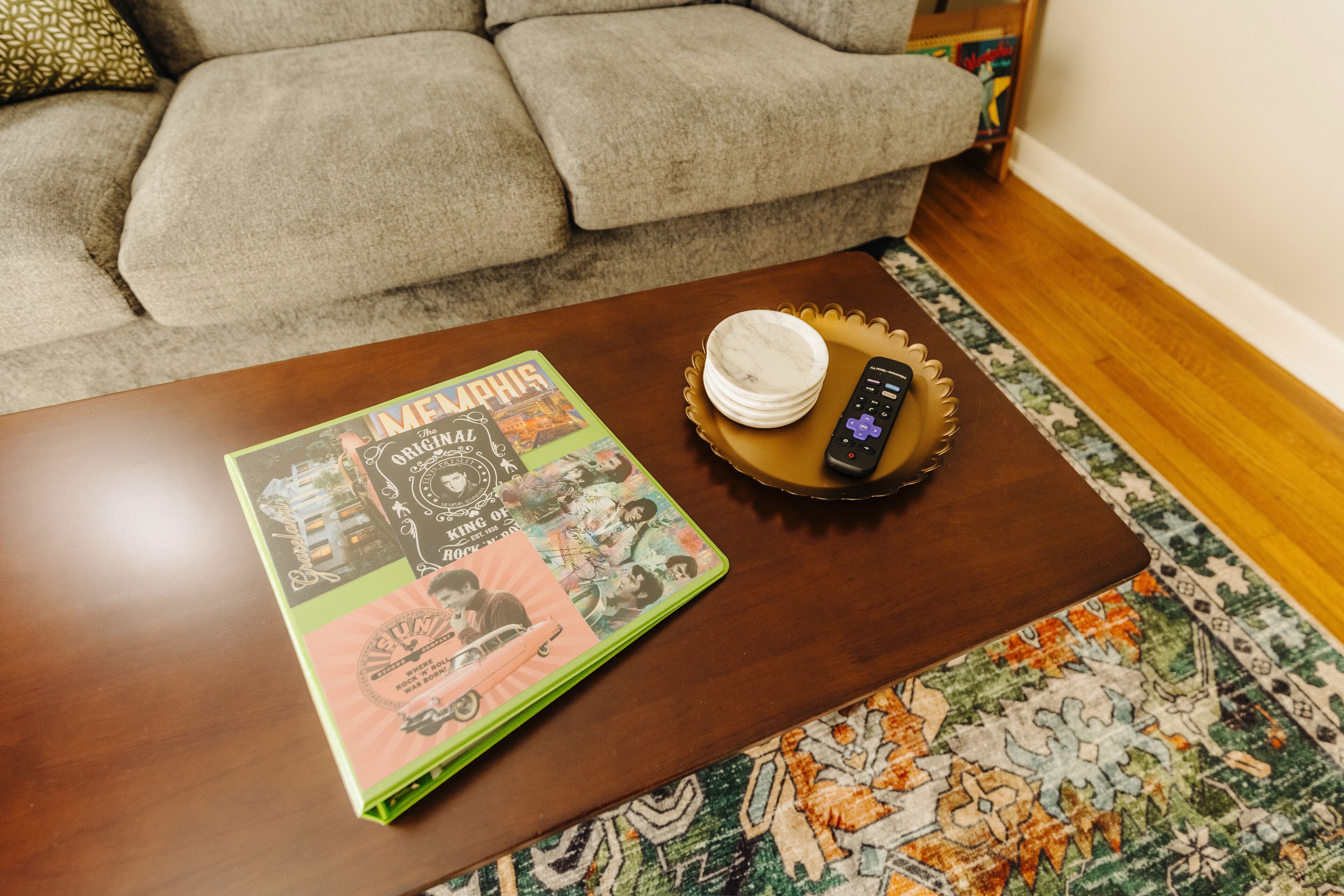 Un salon avec une table basse en bois, un magazine, une télécommande et un tapis à motifs.
