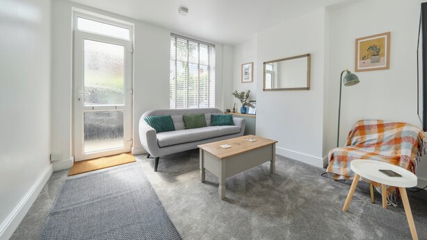 Un salon avec un canapé, une table basse et un fauteuil recouvert d’une couverture.