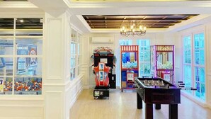 A room with a foosball table, arcade games, and large windows. - Jomtien Seven Seas Cote D'Azure (Muang Pattaya)