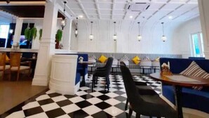 A spacious lobby with a checkered floor, a seating area with a blue sofa, and a dining area with tables and chairs. - Jomtien Seven Seas Cote D'Azure (Muang Pattaya)