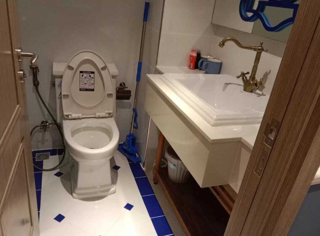 A bathroom with a toilet, sink, and blue-tiled floor.