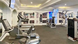 A gym with treadmills, weight machines, and a TV screen. - Jomtien Seven Seas Cote D'Azure (Muang Pattaya)