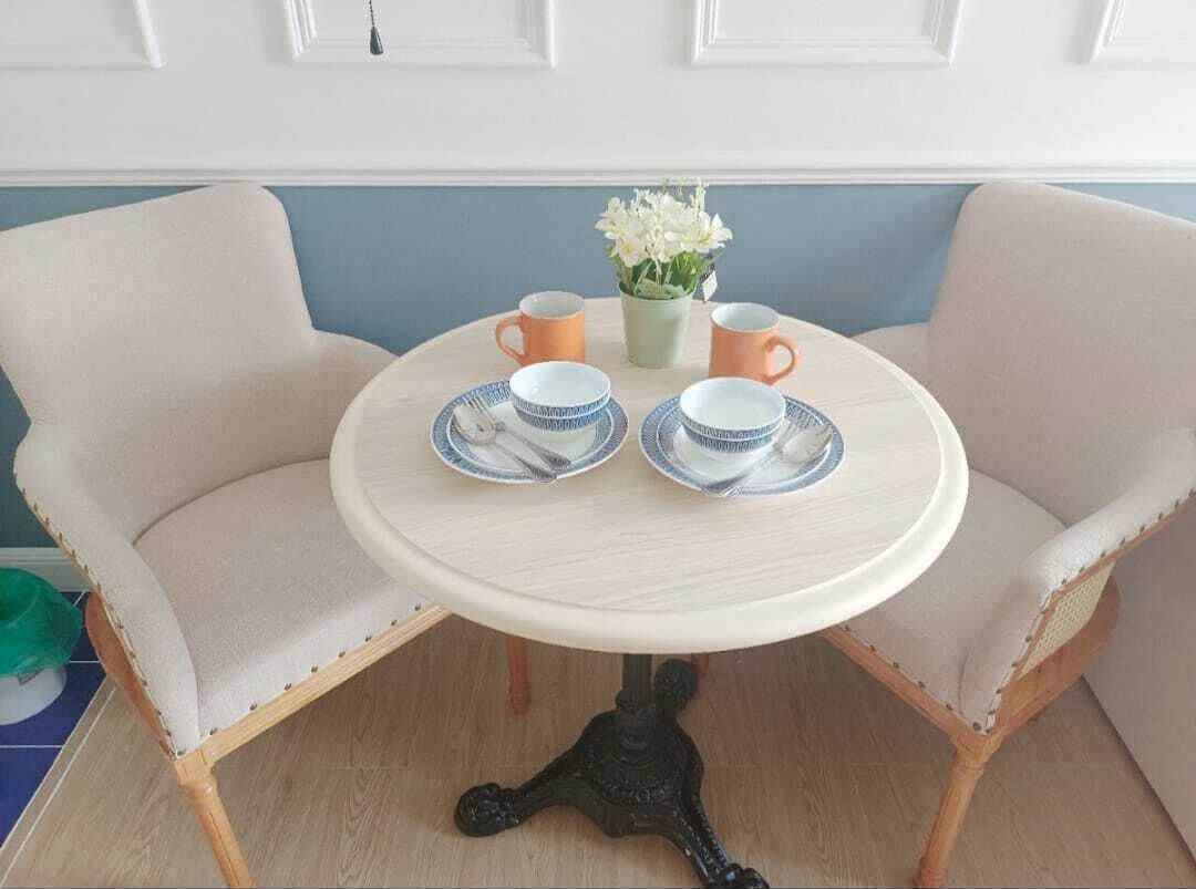 Une table ronde avec deux chaises, un petit vase avec des fleurs et deux tasses.