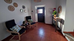 A living room with two chairs, a small table with a plant, and a door leading to another room. - Casa da Pedra (Pedrogão)