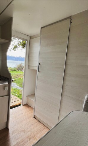 A compact interior with a sliding door leading to a balcony, a kitchenette, and a seating area. - Costa Traful (Villa Traful)