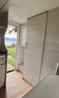 Un interior compacto con una puerta corredera que da a un balcón, una kitchenette y una zona de estar.