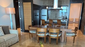 A modern living room with a sofa, a wooden coffee table with a plant, and a dining area with chairs and a table.