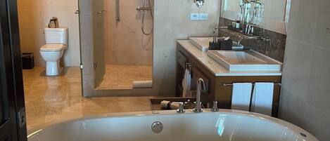 Un baño moderno con una bañera grande, ducha a ras de suelo y tocador con espejo.