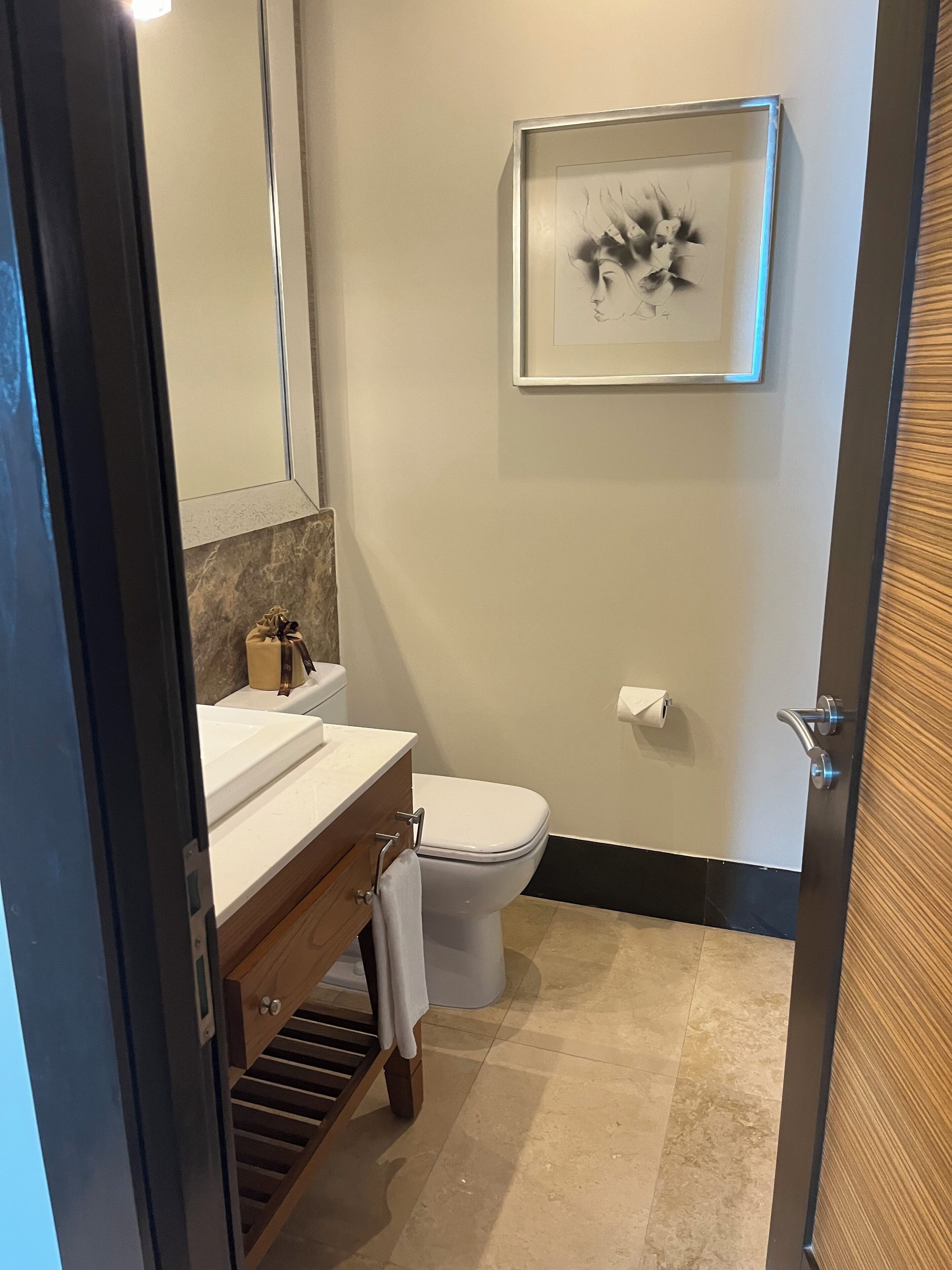 Een moderne badkamer met een wit wastafelmeubel, een toilet en een kunstwerk in een lijst aan de muur.
