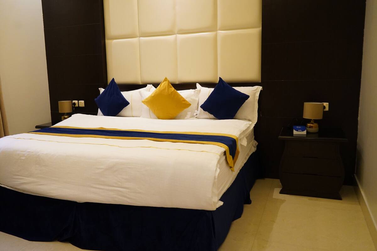 A hotel room with a large bed, a nightstand, and a headboard.
