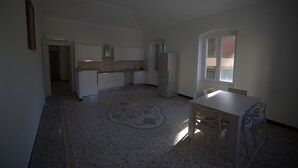 A spacious kitchen with white cabinets, a refrigerator, and a dining area with a table and chairs. - Bosmi Bed&Language Liguria (Sori)