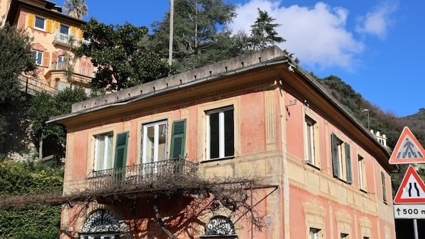 A red car parked in front of a building with a balcony and a pedestrian crossing sign nearby. - Bosmi Bed&Language Liguria (Sori)
