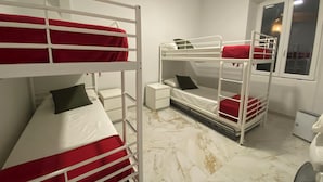 A room with bunk beds, a small bedside table, a nightstand, and a window with a view of the outside. - Bosmi Bed&Language Liguria (Sori)
