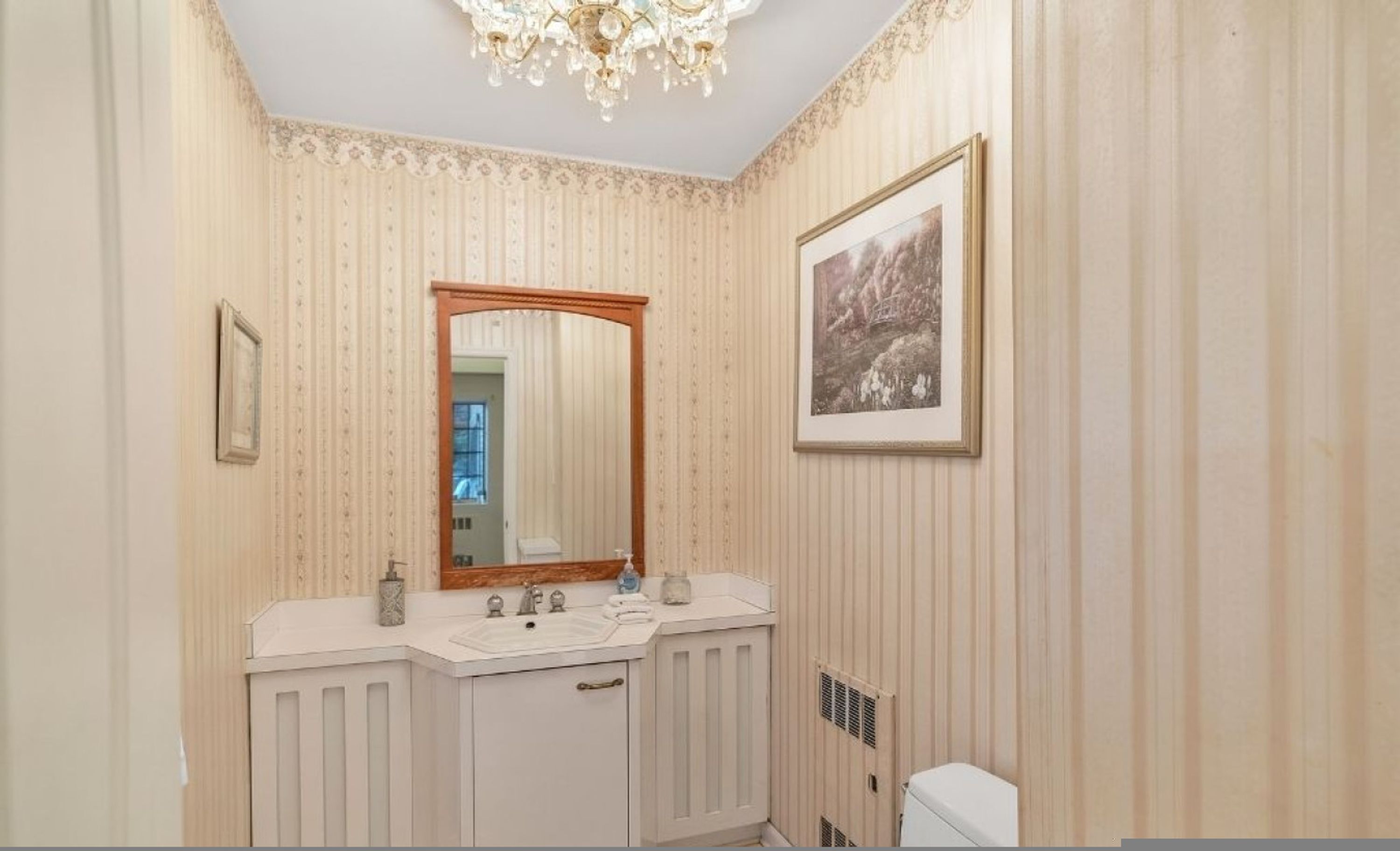 A bathroom with a vanity, mirror, and a framed picture on the wall.