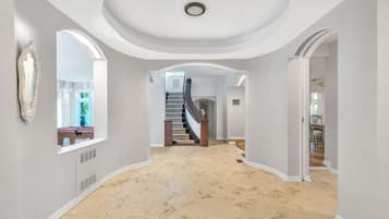 Ein geräumiger Korridor mit Marmorboden, einer Treppe und einem großen Spiegel an der linken Wand.