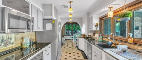 A kitchen with a checkered floor, modern appliances, and pendant lighting.