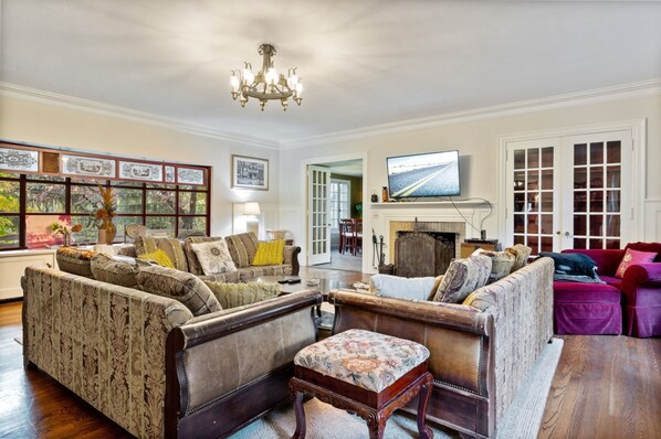A traditional living room with a fireplace, multiple sofas, and a television.