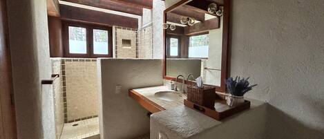 A bathroom with a wooden ceiling, a sink, a mirror, and a window.
