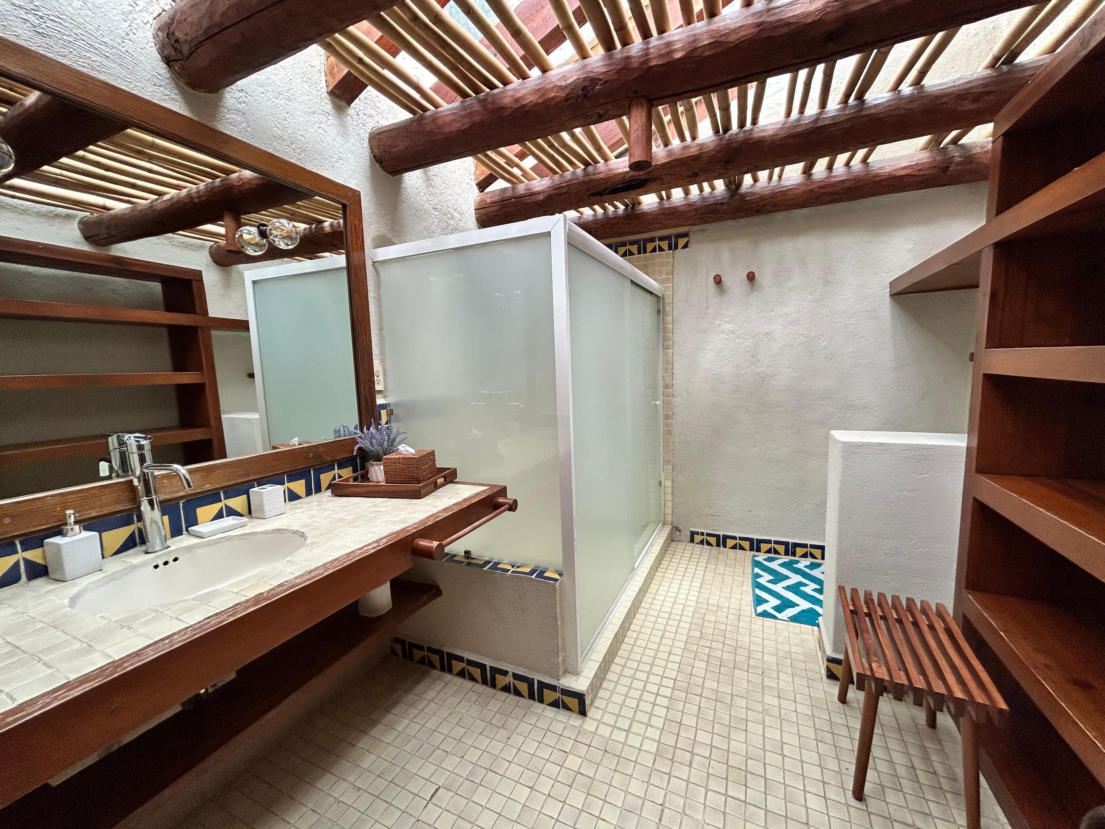 Une salle de bain avec un meuble-lavabo en bois, un grand miroir et une cabine de douche.