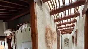 Um corredor estreito com uma cama à esquerda e teto de madeira.