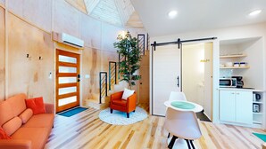 A modern living room with a wooden floor, a sofa, a coffee table, a chair, and a staircase leading to another room. - 🌟Planetarium Treehouse🌟Stargazing Observatory with Beaver Lake Views (Springdale)