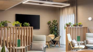 Una sala de estar moderna con un televisor de pantalla plana, asientos cómodos y plantas en macetas.
