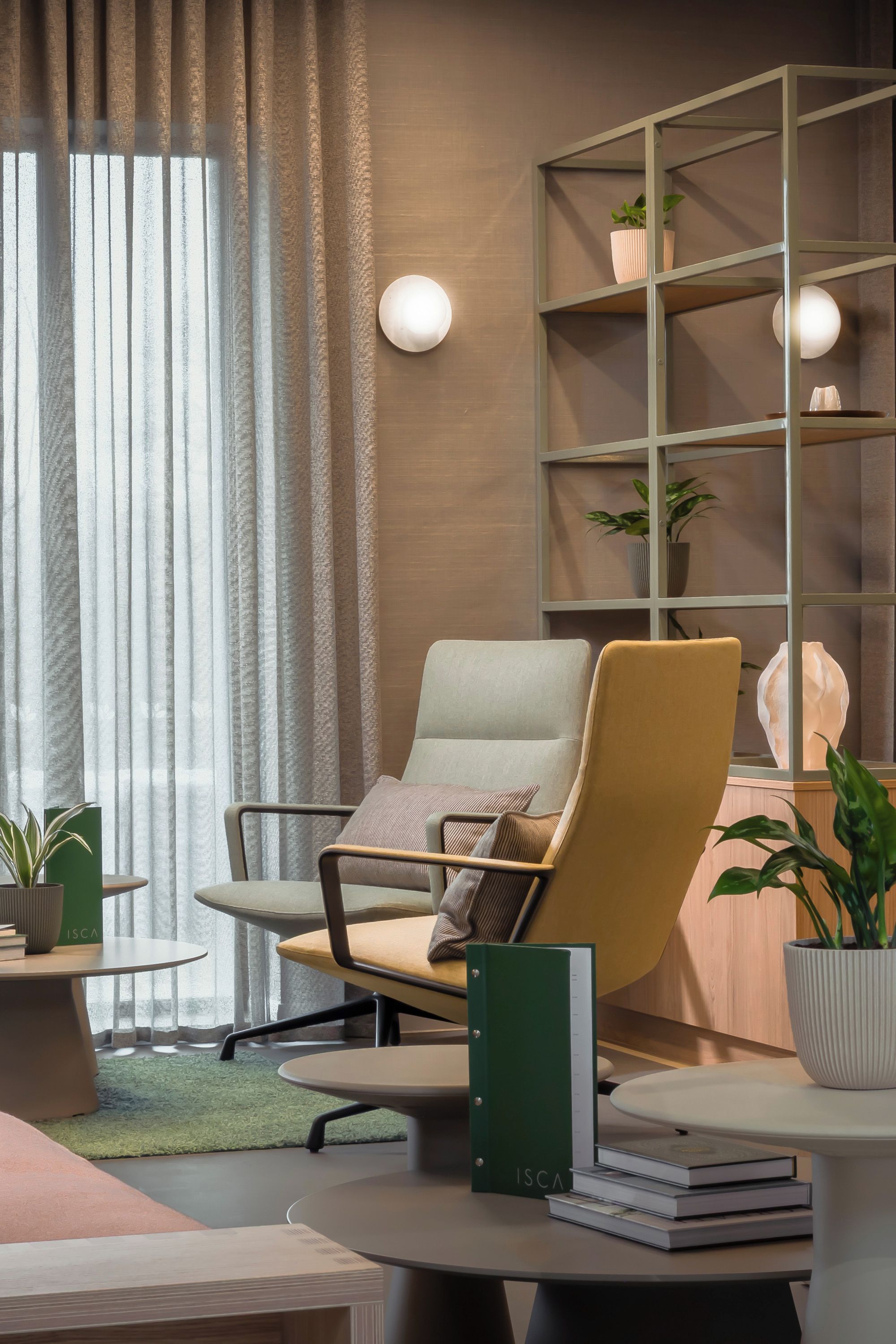 Un espacio de oficina moderno con una silla cómoda, una estantería y una pequeña mesa con libros y una planta.