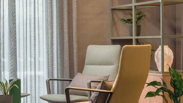 Un espacio de oficina moderno con una silla cómoda, una estantería y una pequeña mesa con libros y una planta.