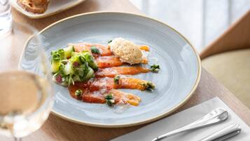 Un plato de comida con salmón, vegetales verdes y una cucharada de salsa sobre un plato de cerámica.