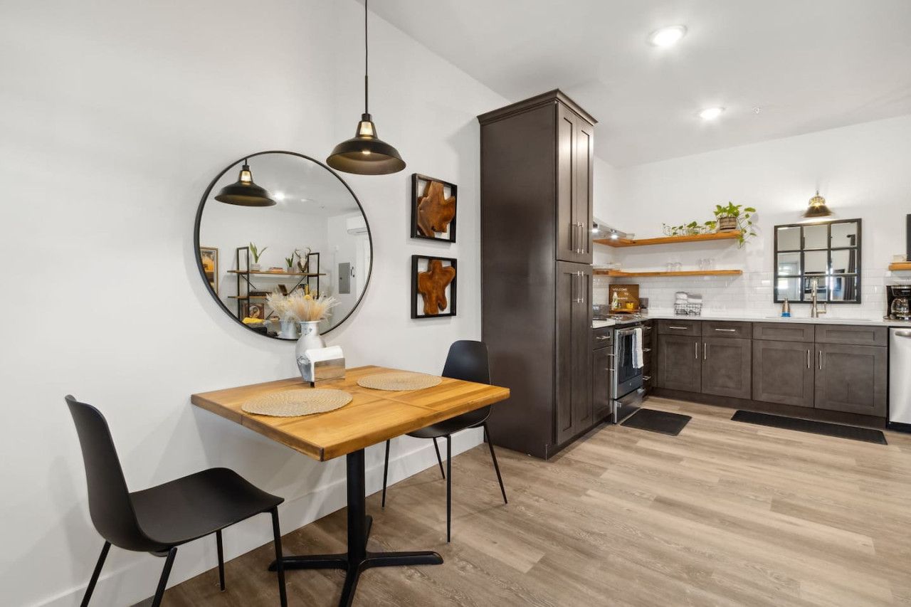 Una cocina moderna con armarios oscuros, una mesa de comedor de madera y sillas negras.