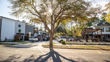 A street view with a tree in the center, buildings on either side, and parked cars.