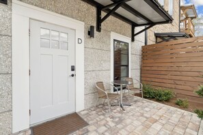 A white door with a small window, a glass door, and a patio area with a table and chairs.