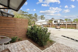 A patio area with a wooden fence, a metal table, and a small garden.