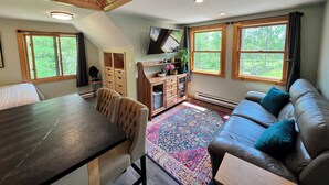 Ein gemütliches Zimmer mit Esstisch, Stühlen, einer Couch und einem an der Wand befestigten Fernseher.