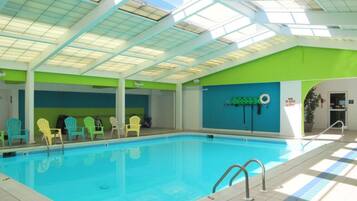 Una piscina interior con techo de tragaluces, paredes verdes y una estación de socorristas.