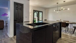 A modern kitchen with a large island, dark cabinetry, and a pendant light fixture. - 4BR/3BA Cabin w/ Games & Hot Tub, Near Smoky Mtns (Kodak)