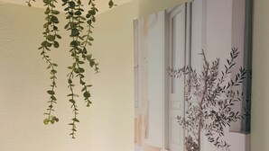 Une pièce avec une plante suspendue, un tableau encadré représentant une plante en pot et une lampe.