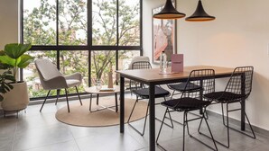A modern dining area with a wooden table, black wire chairs, and pendant lights. - Ganesh by Wynwood House (Medellín)