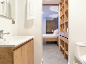 A modern bathroom with a white sink, wooden cabinets, and a visible toilet. - Ganesh by Wynwood House (Medellín)