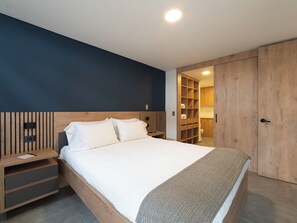 A modern bedroom with a bed, wooden headboard, bedside tables, and a built-in wardrobe. - Ganesh by Wynwood House (Medellín)