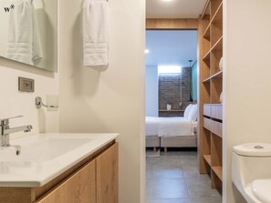 Ein modernes Badezimmer mit einem großen Waschbecken, Holzschränken und einer Toilette.
