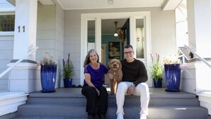 Eine Veranda mit Treppe, Blumentöpfen und einem Hund.