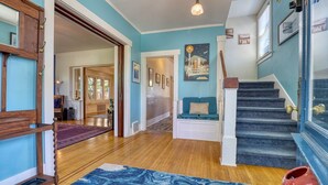 Ein geräumiger Wohnbereich mit Holzböden, einer blauen Akzentwand, einer Treppe und einer Sitzecke mit einem blauen Sofa.