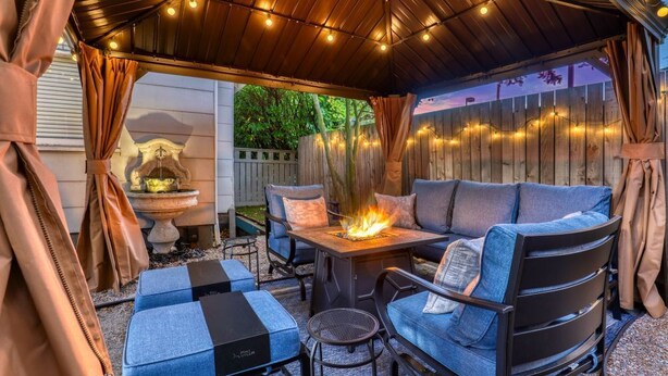 Ein überdachter Patio-Bereich mit Feuerstelle, Sitzgelegenheiten und Lichterketten.
