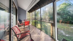 Eine überdachte Terrasse mit Blick auf einen Garten, ausgestattet mit Tisch und Stühlen.