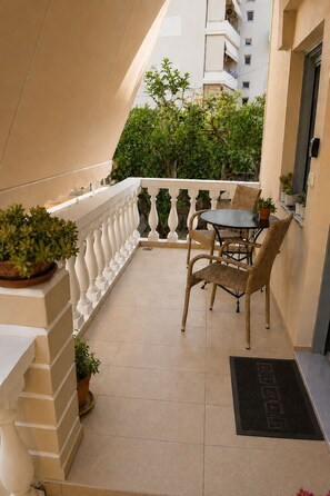 Un balcon avec une table et des chaises, des plantes en pot et une balustrade blanche.
